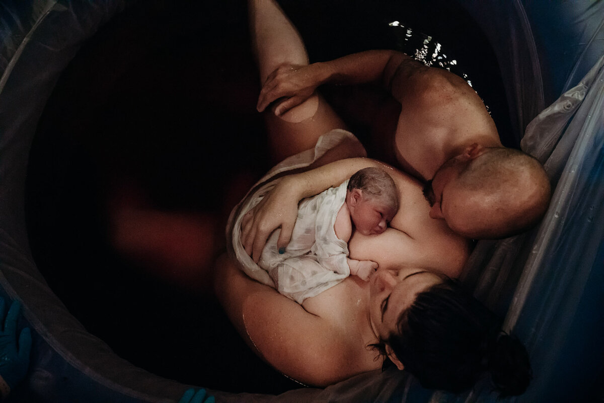 man and woman in birth pool holding newborn