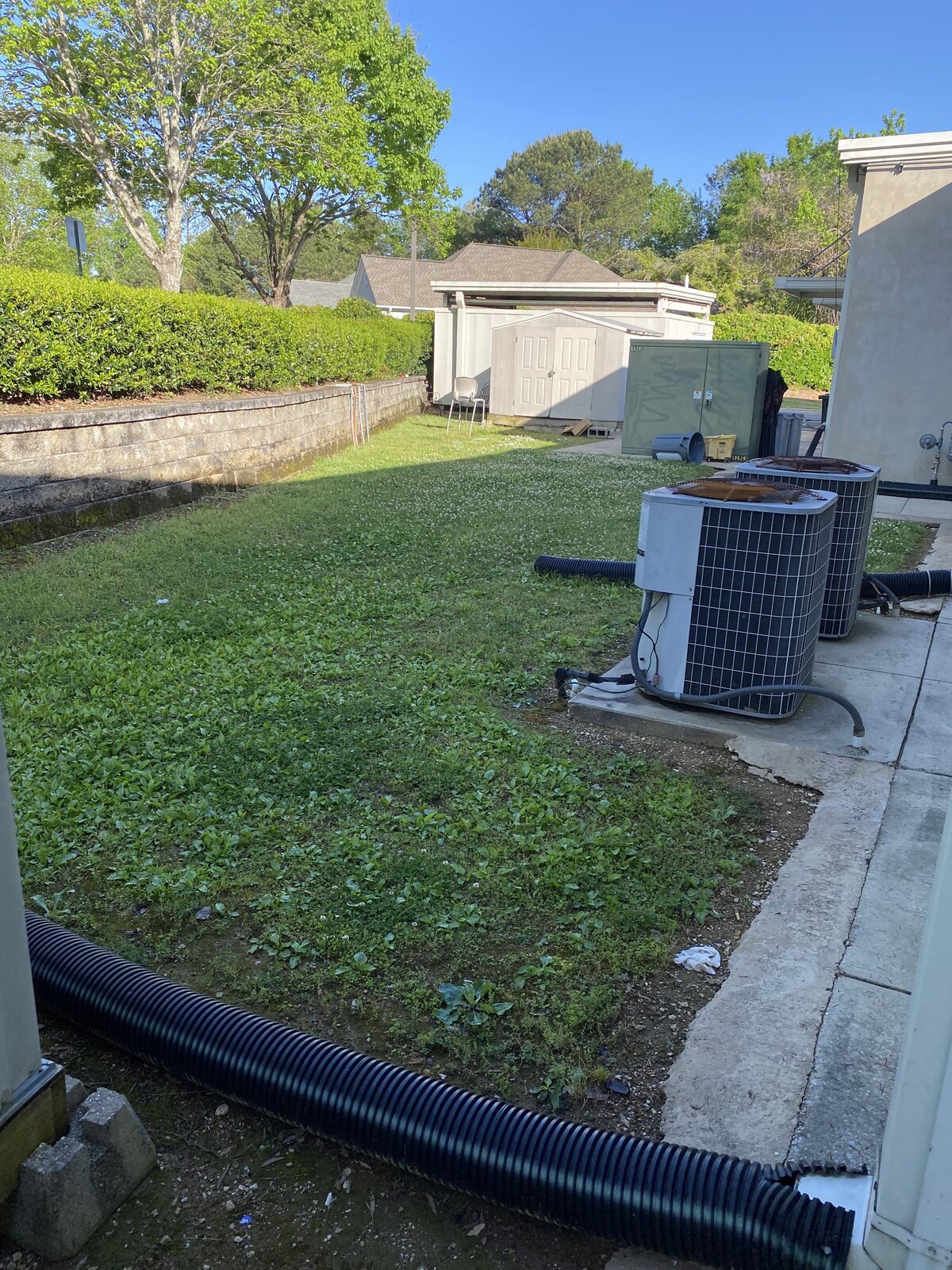 drainage-hose-next-to-air-conditioning-unit-in-grassy-backyard