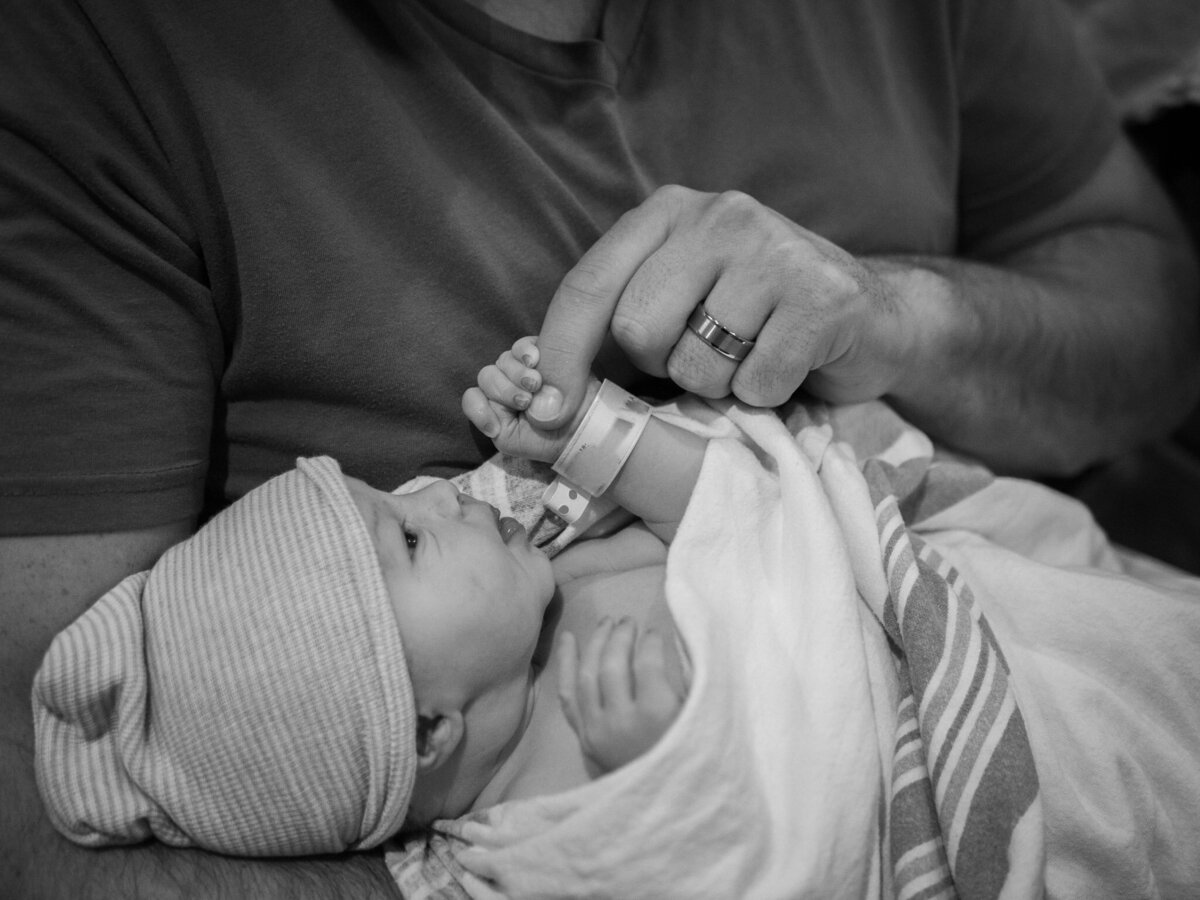 a newborn baby grips his father's finger  within hours of being born.