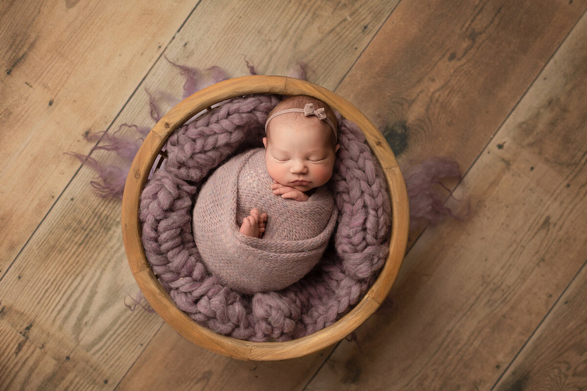 baby girl in a purple set up for her photos in our denver newborn studio