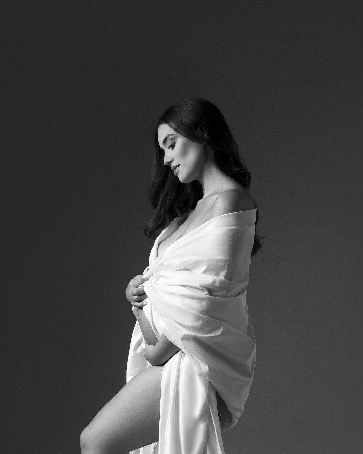 beautiful pregnant woman draped in white fabric.