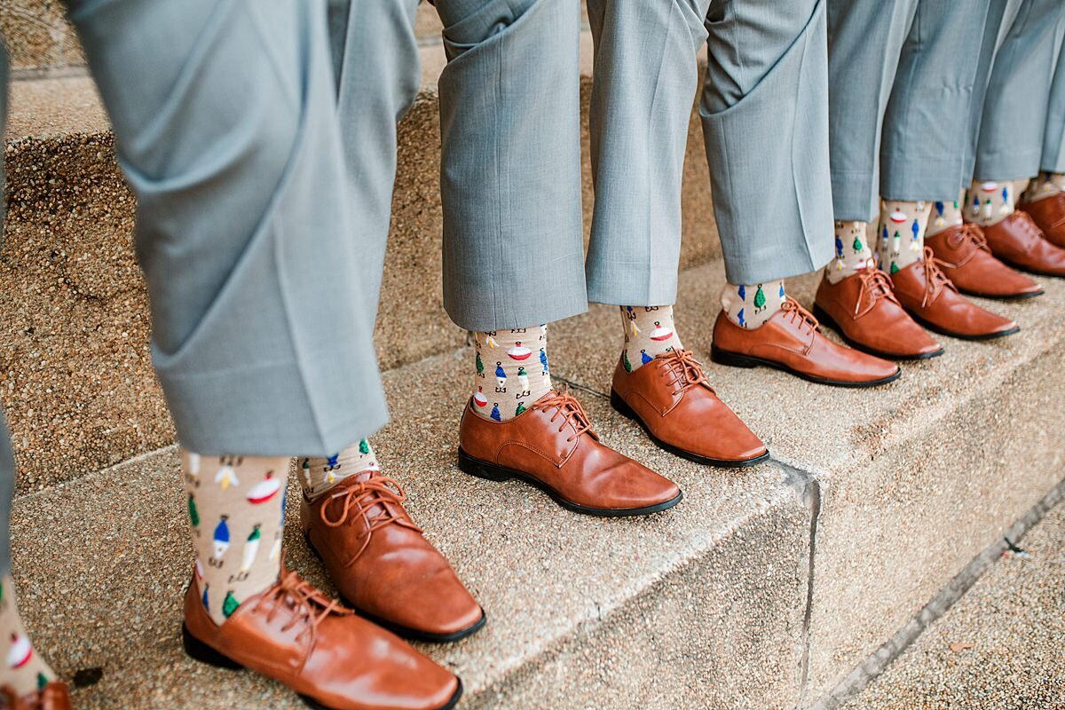 Groomsmen wearing gray pants and light brown dress shoes show off their tan socks with fishing lures standing on the steps of The Parthenon in Nashville.