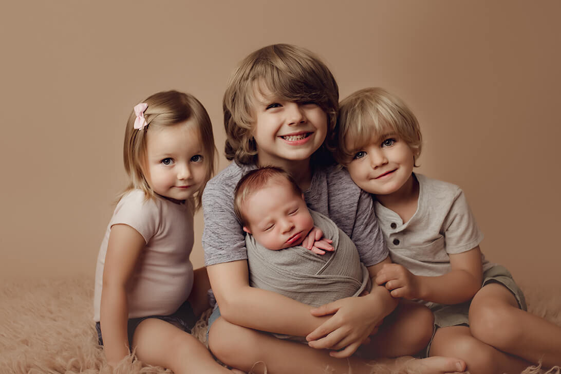 Two brothers and a sister holding a new baby brother