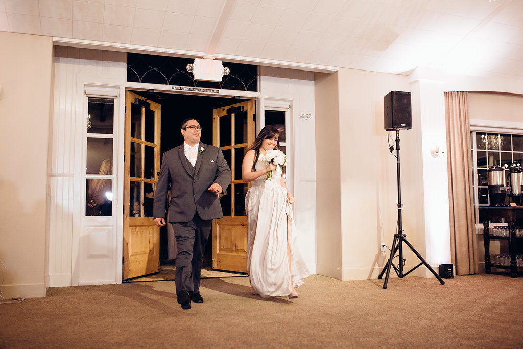 Wedding Photograph Of Groomsman And Bridesmaid Holding Her Dress While Entering The Reception Hall Los Angeles