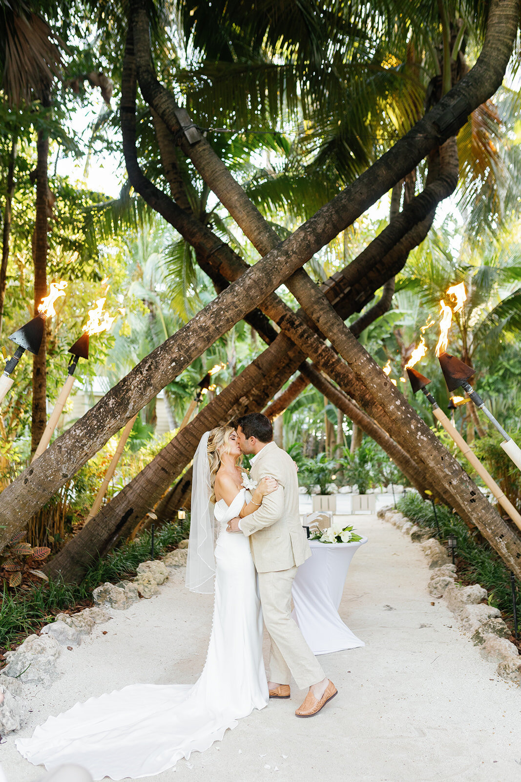 Monica and Austyn share their first kiss as newlyweds under a stunning wooden arch at their Islamorada wedding ceremony.