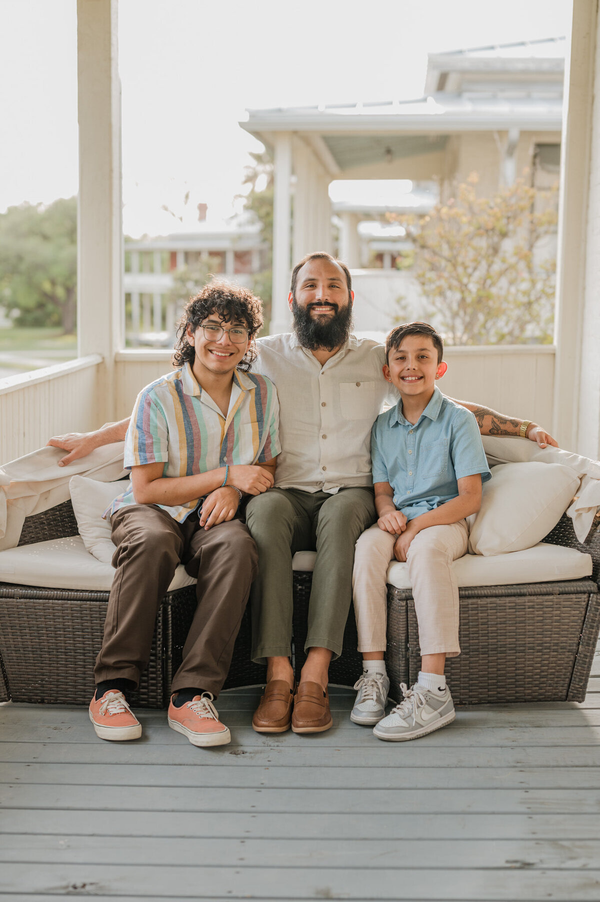Dad and sons sit on a couch for family pictures.