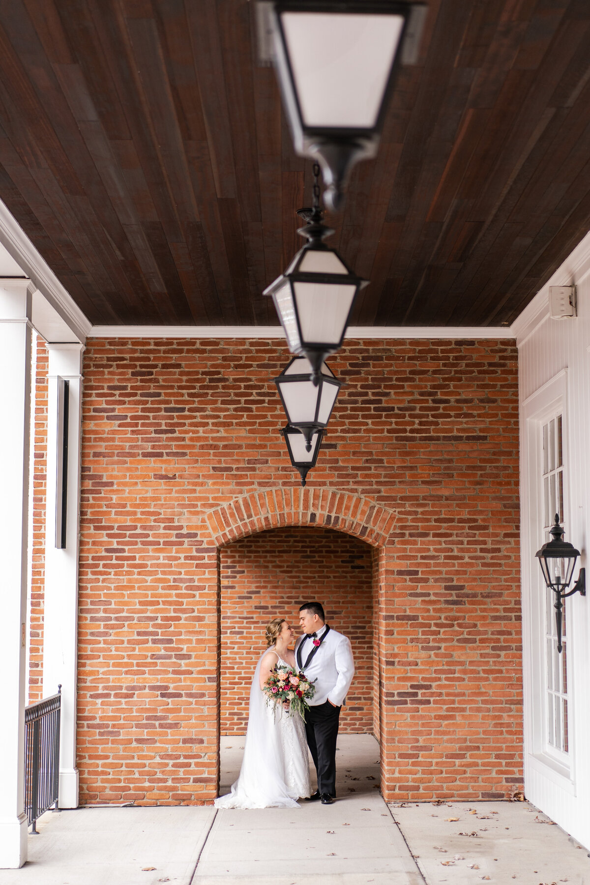 Bride and groom look lovingly at each other under a brick arch at Nationwide Hotel and Conference Center in Lewis Center, Ohio.