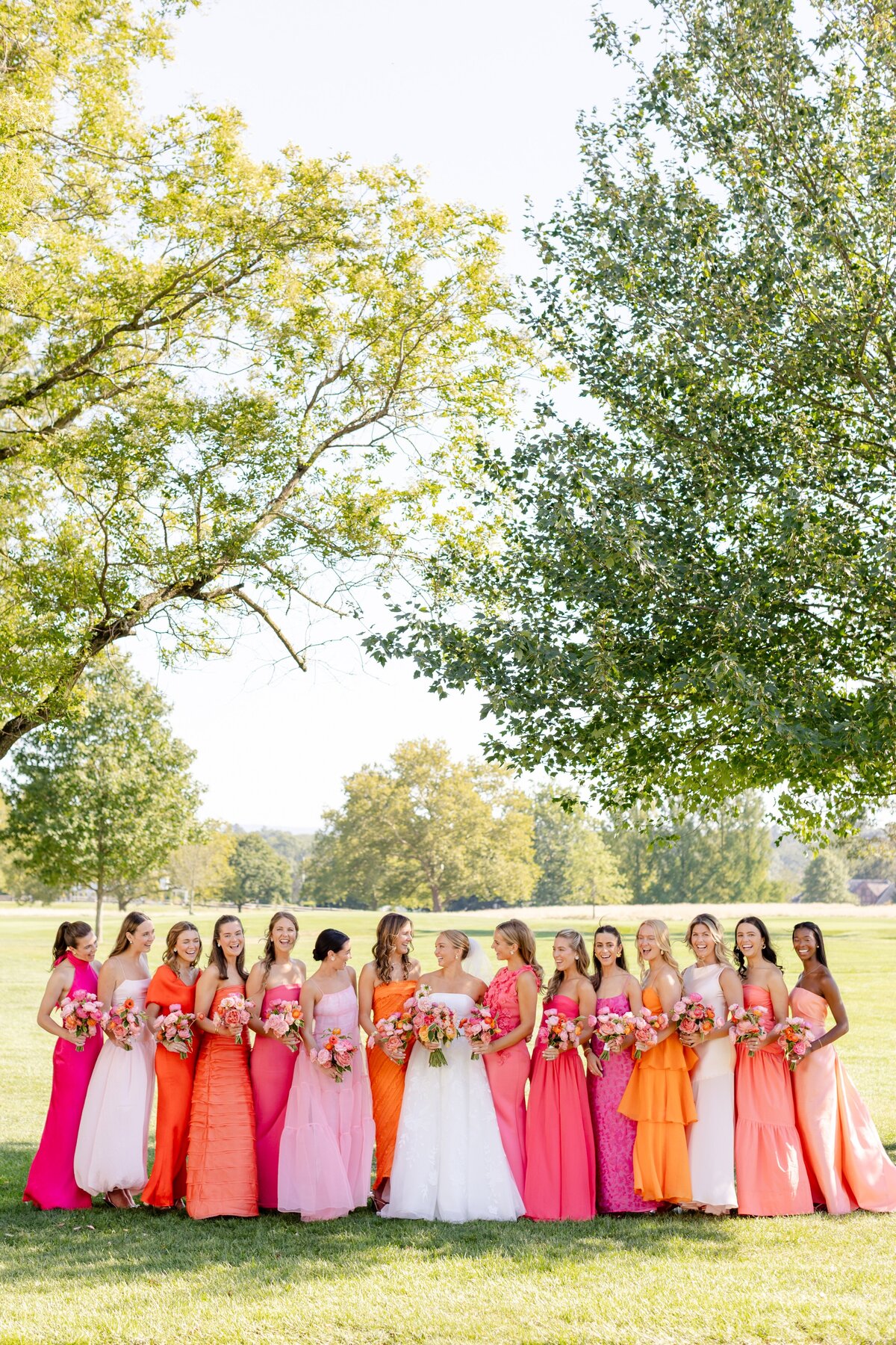 bride and bridesmaids in orange, pink and yellow dress during outdoor portraits