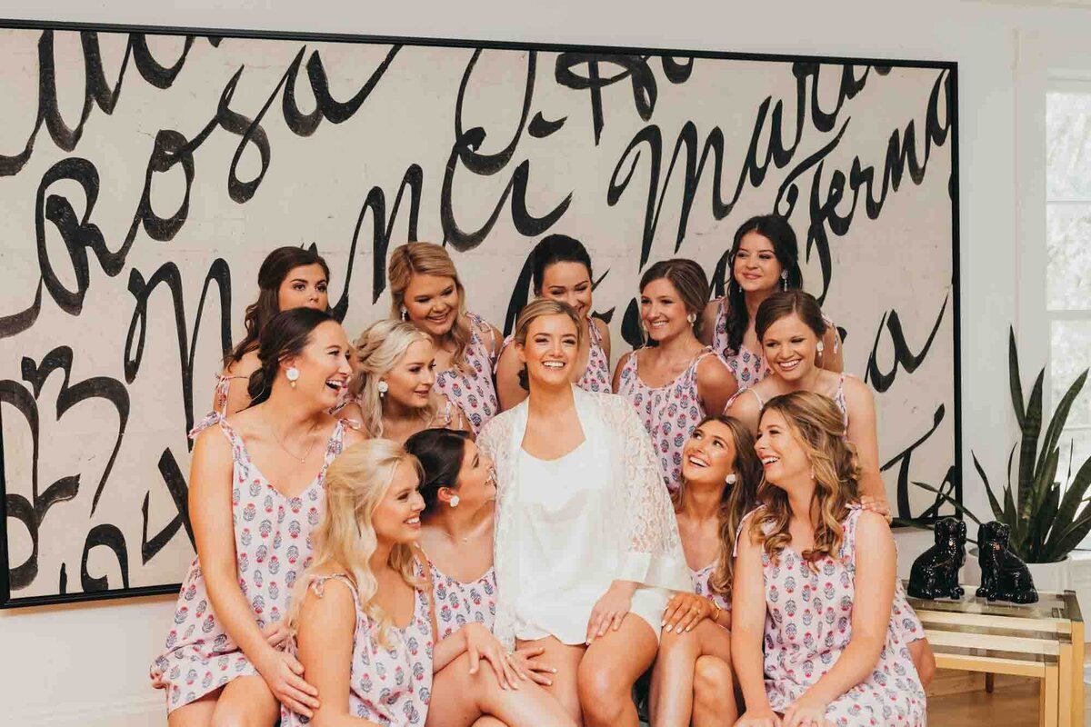 bride is surrounded by her bridesmaids on her wedding day, in their matching pajamas