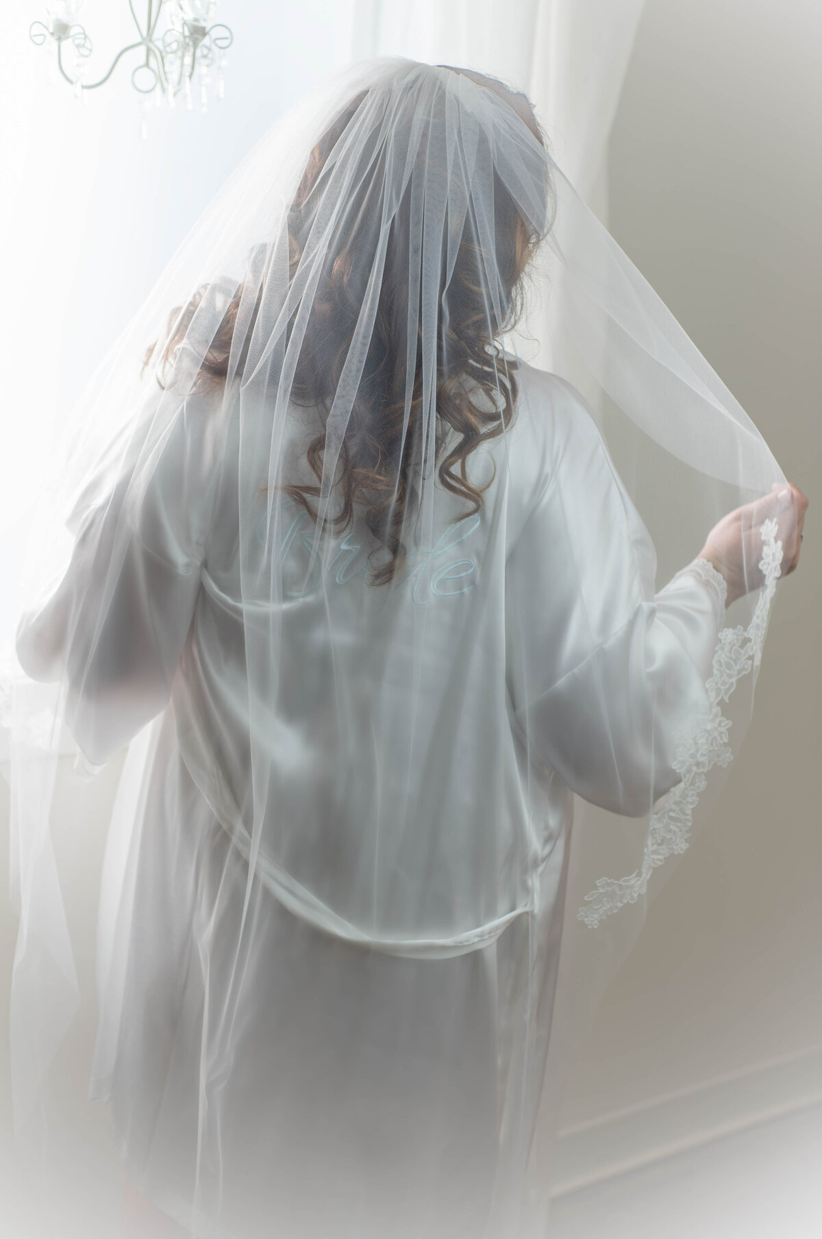 Bridal boudoir photo of bride in a robe and veil