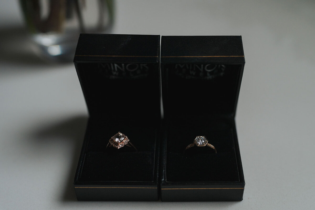 Two wedding rings sit side by site in wooden boxes 