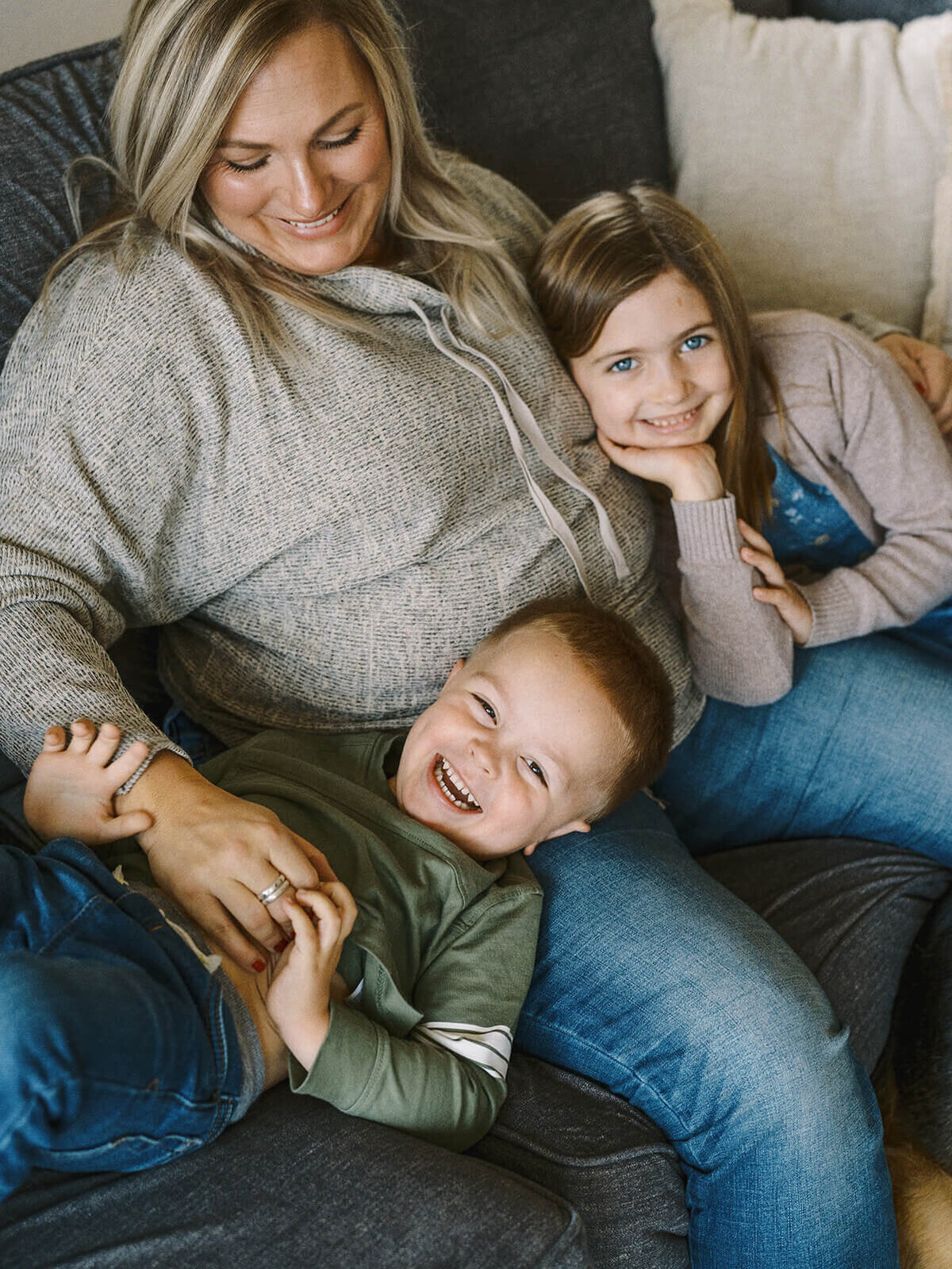 A woman sitting with a young boy and girl during an at home family portrait session.