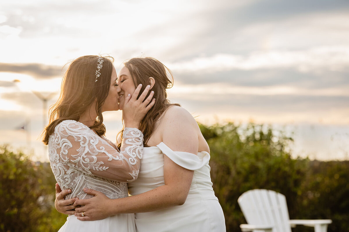 Two brides kissing at sunset