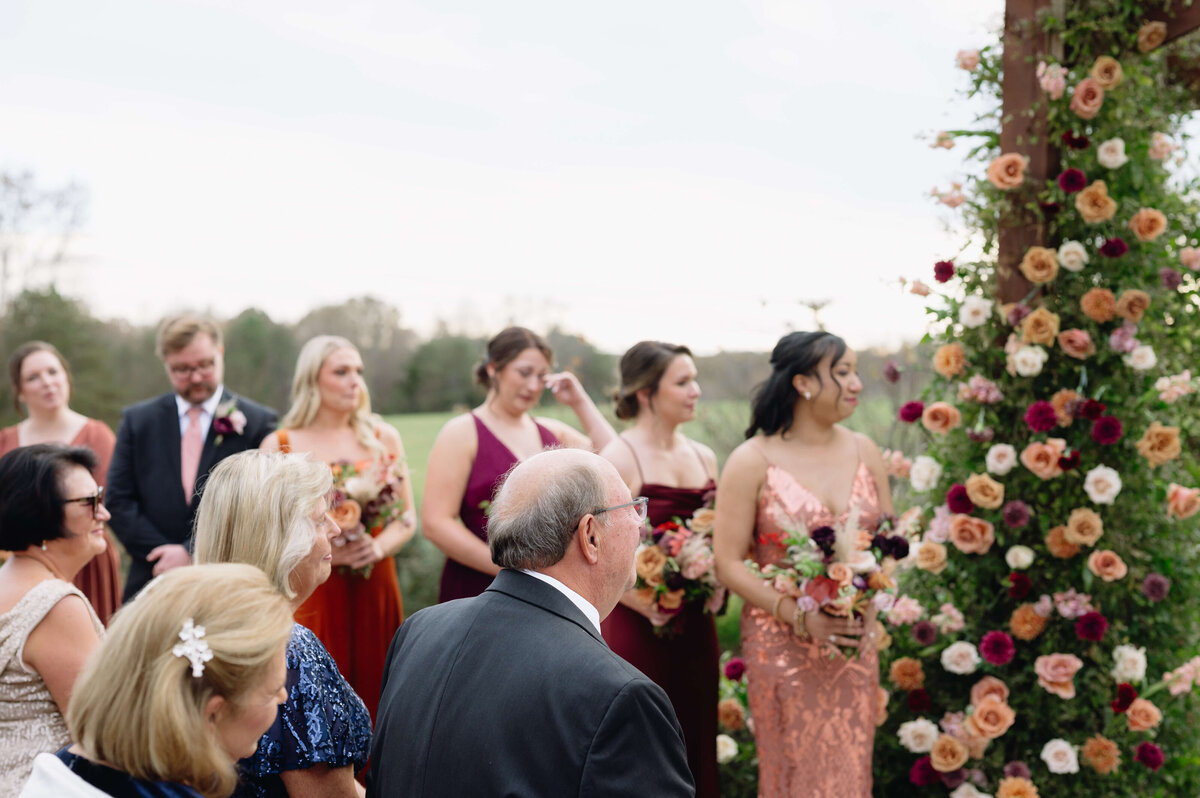 Shenandoah National Park wedding ceremony with bridesmaids in red and pink bridesmaids dresses standing in a line behind the bride with the green hills behind them