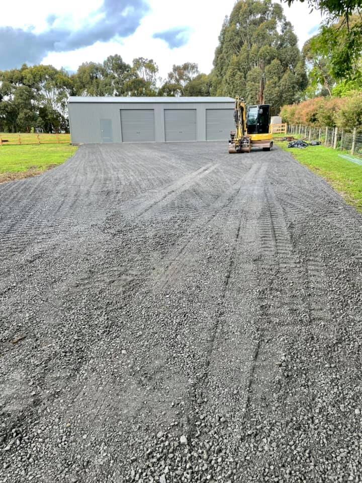 Driveway and excavator constructing new driveway and spreading quarry products