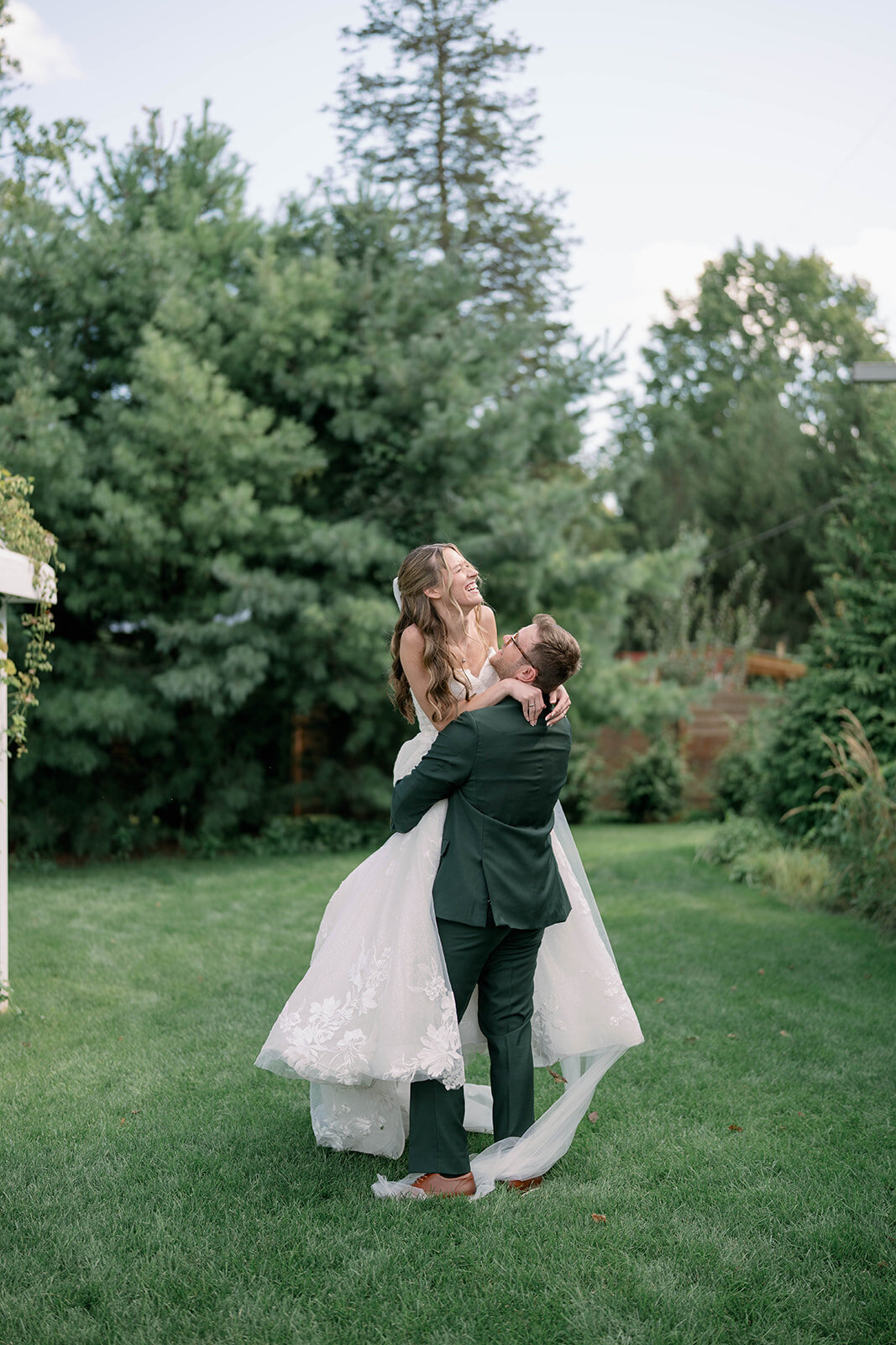 Groom lifting and spinning the bride while she laughs during portraits at The Ivy House.