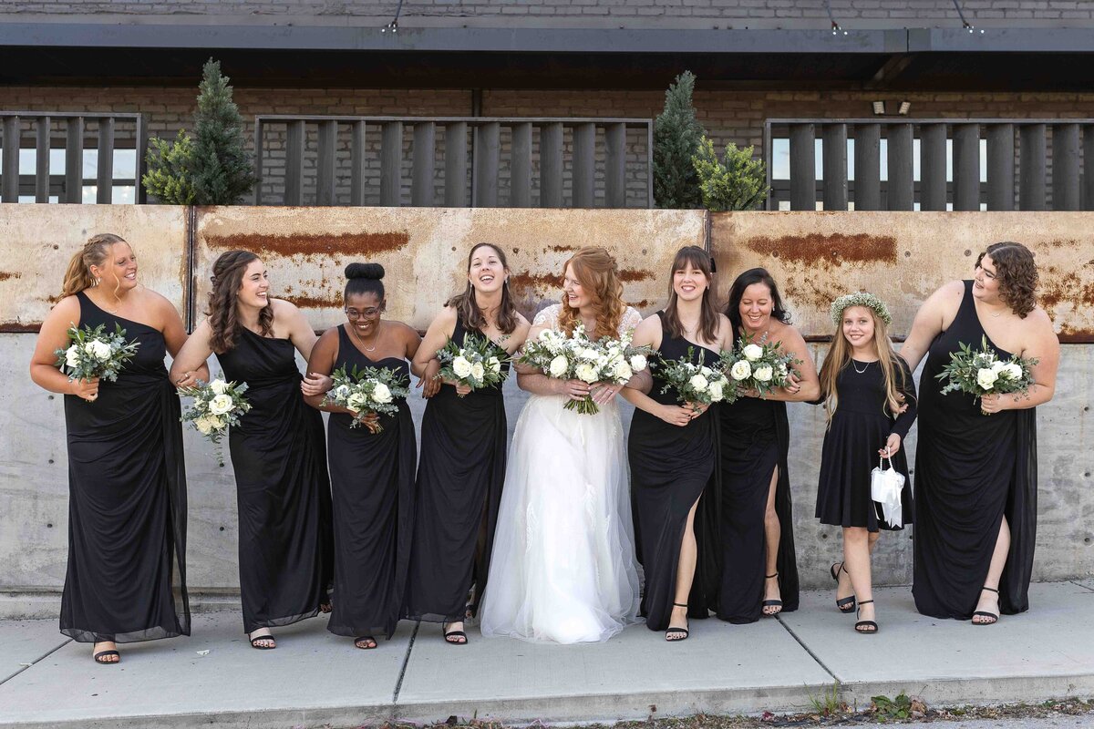 Bride with bridesmaids laughing with each other and holding wedding bouquets 