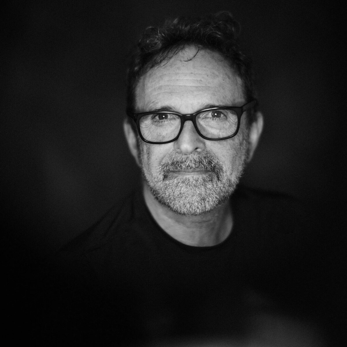 A man with glasses looking straight forward in black and white
