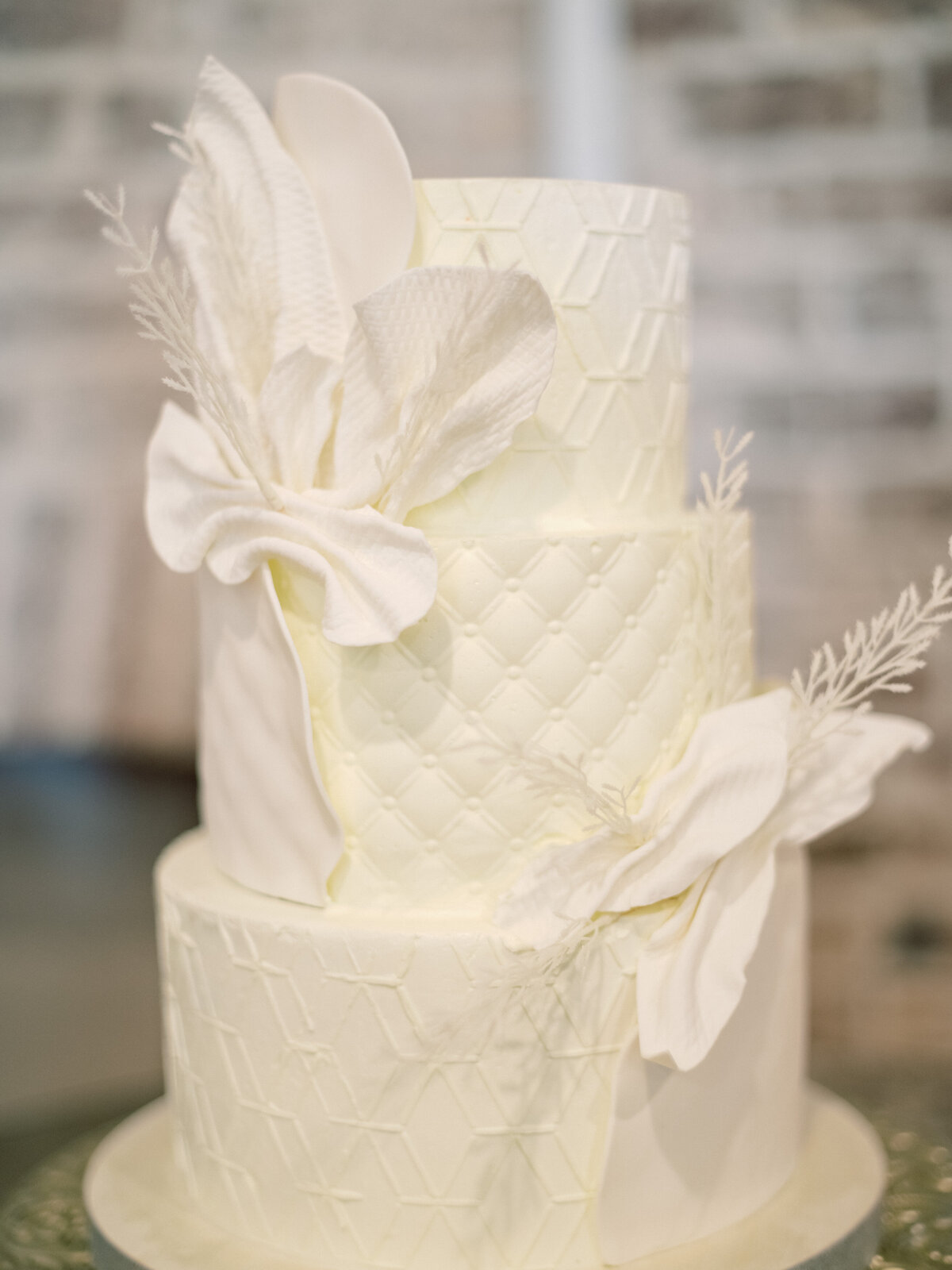 A stunning three-tier white wedding cake featuring intricate designs and beautiful floral accents, perfect for a classy celebration and a memorable event.