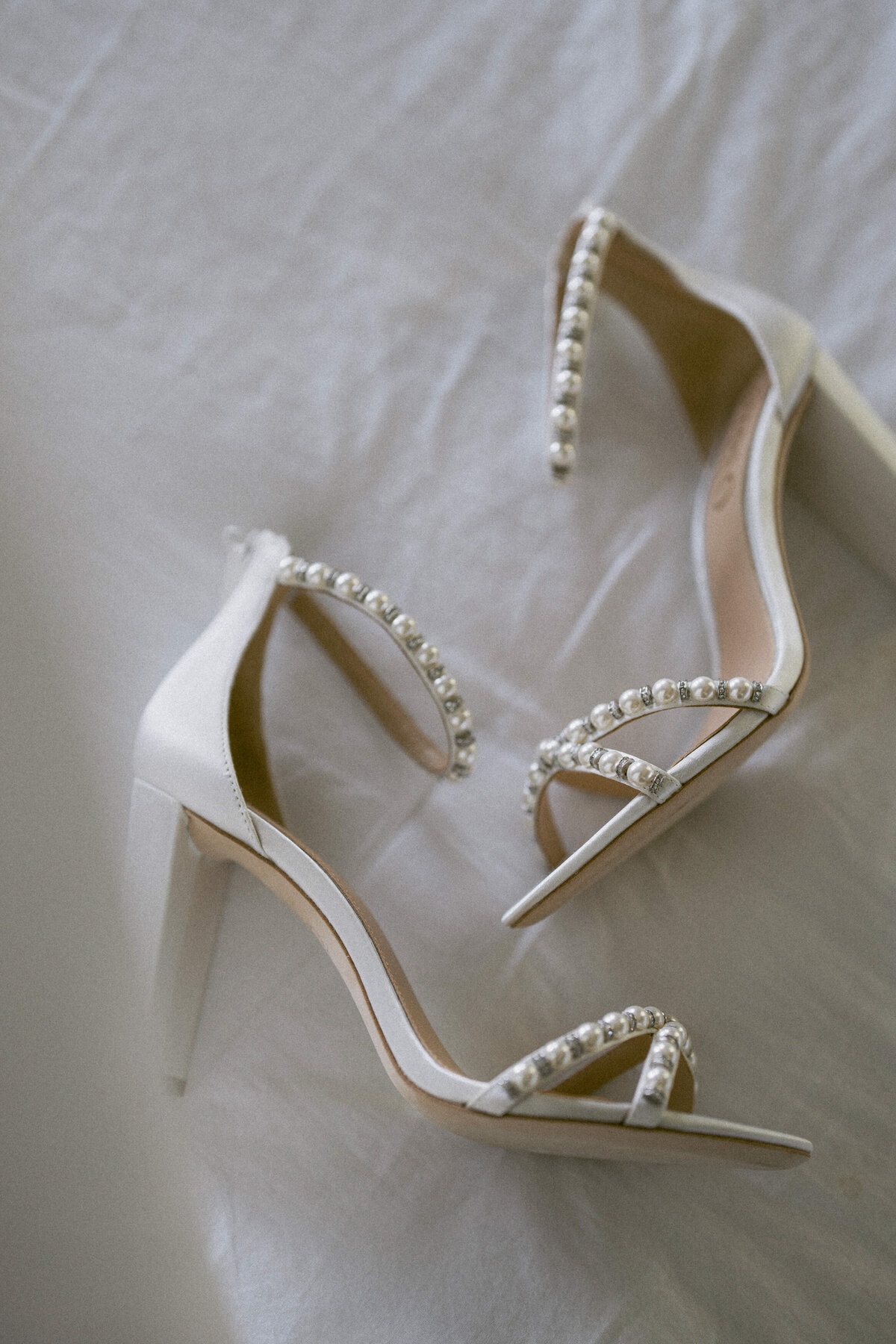 Detail of pearl heels sitting on a bed