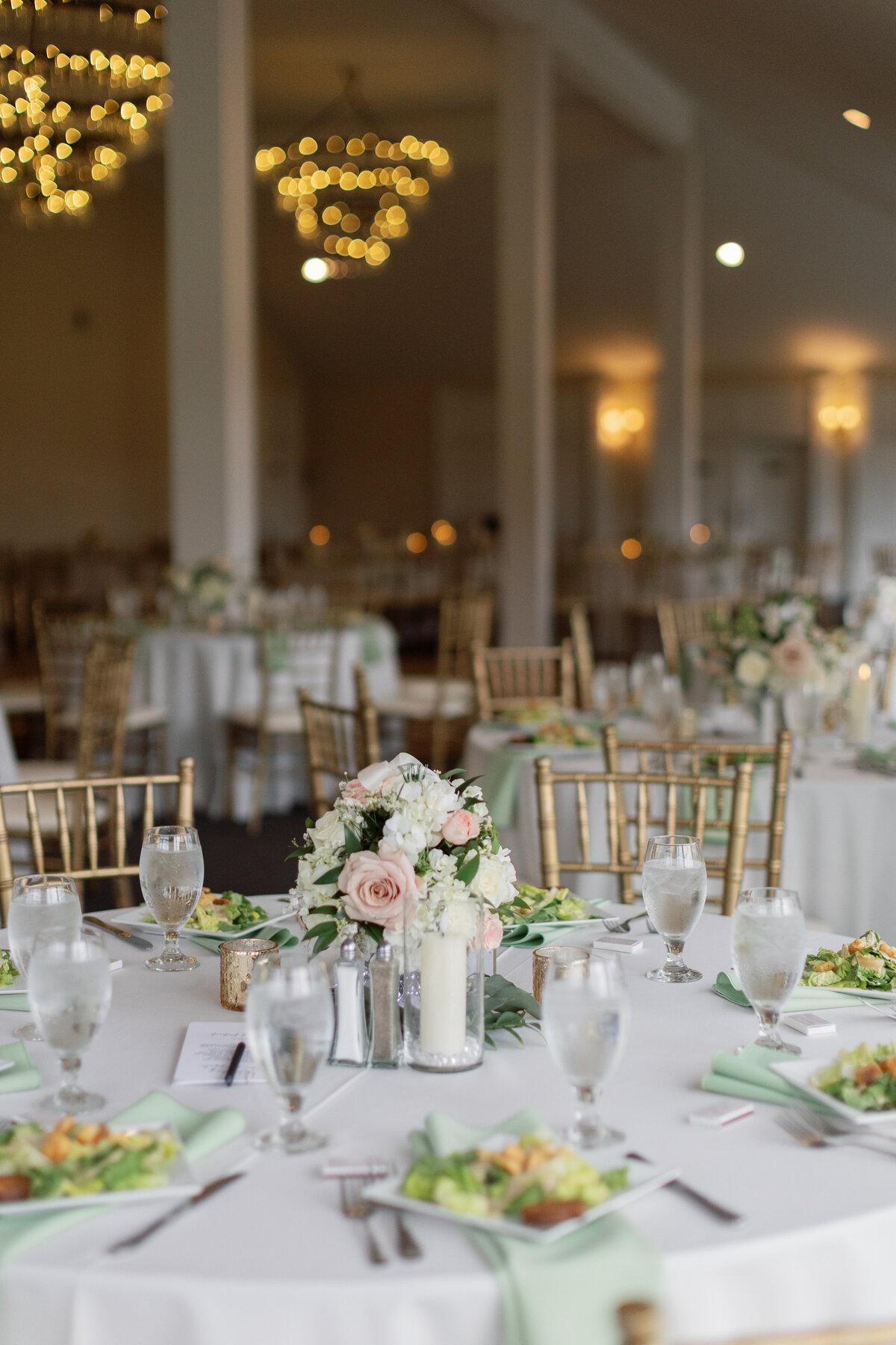Gold accent chairs with spring roses and elegant plates line the tablescape for a spring wedding