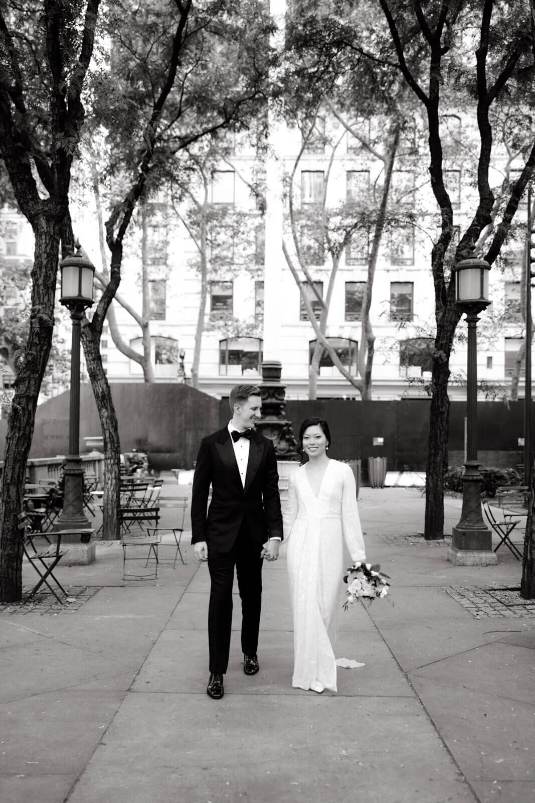 The bride and the groom are happily walking at the New York Public Library Park. Image by Jenny Fu Studio