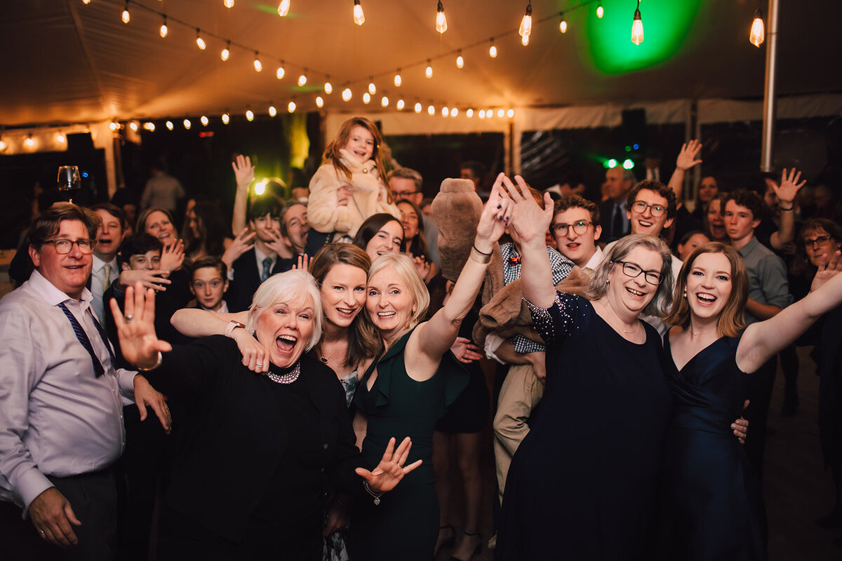 Wedding guests smile on the dance floor