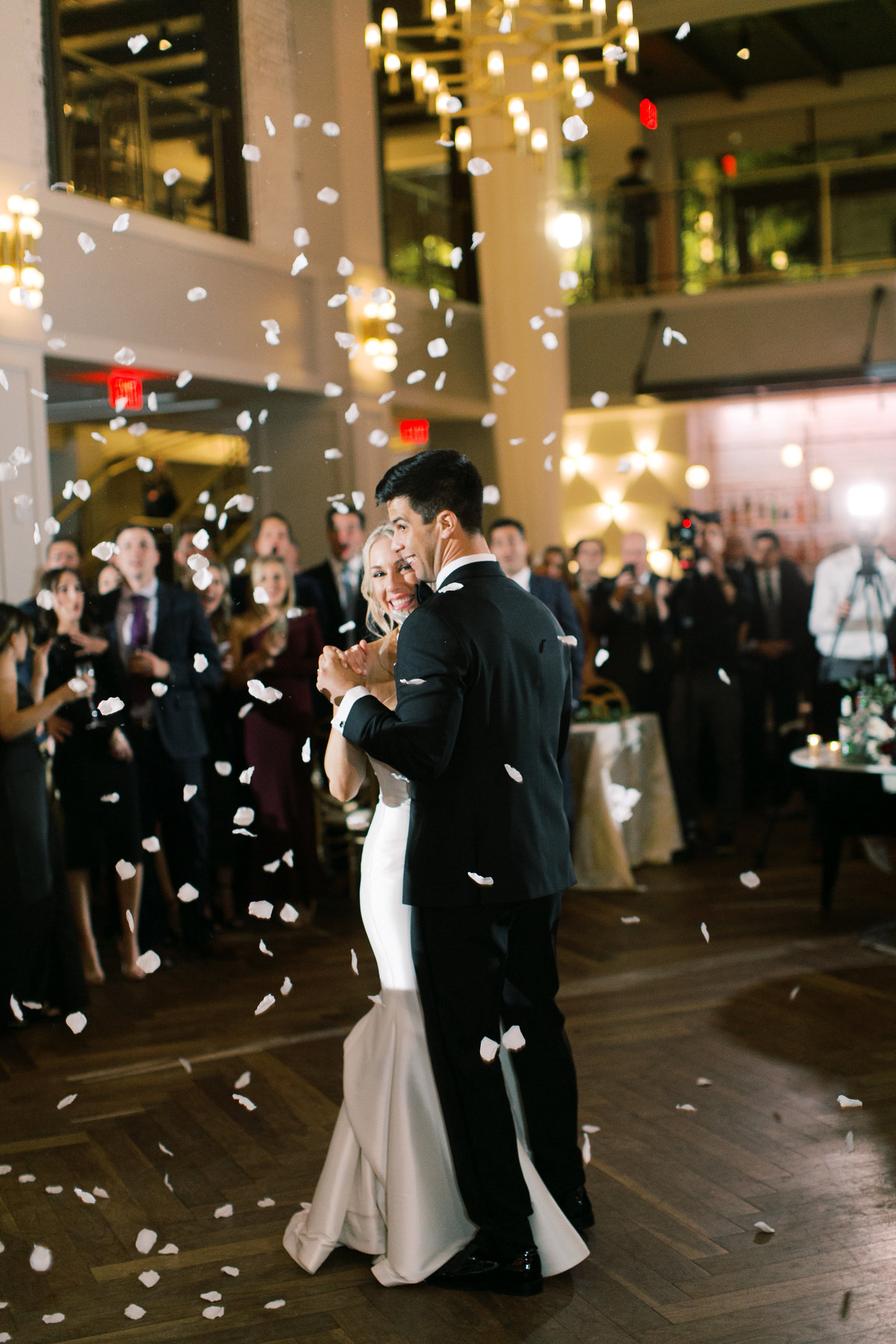 bride and groom dancing during first dance as flower petals fall from above them