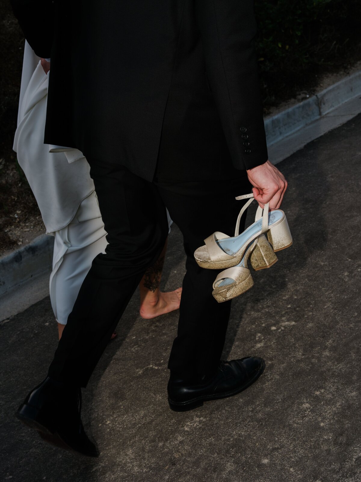 groom carrying brides shoes