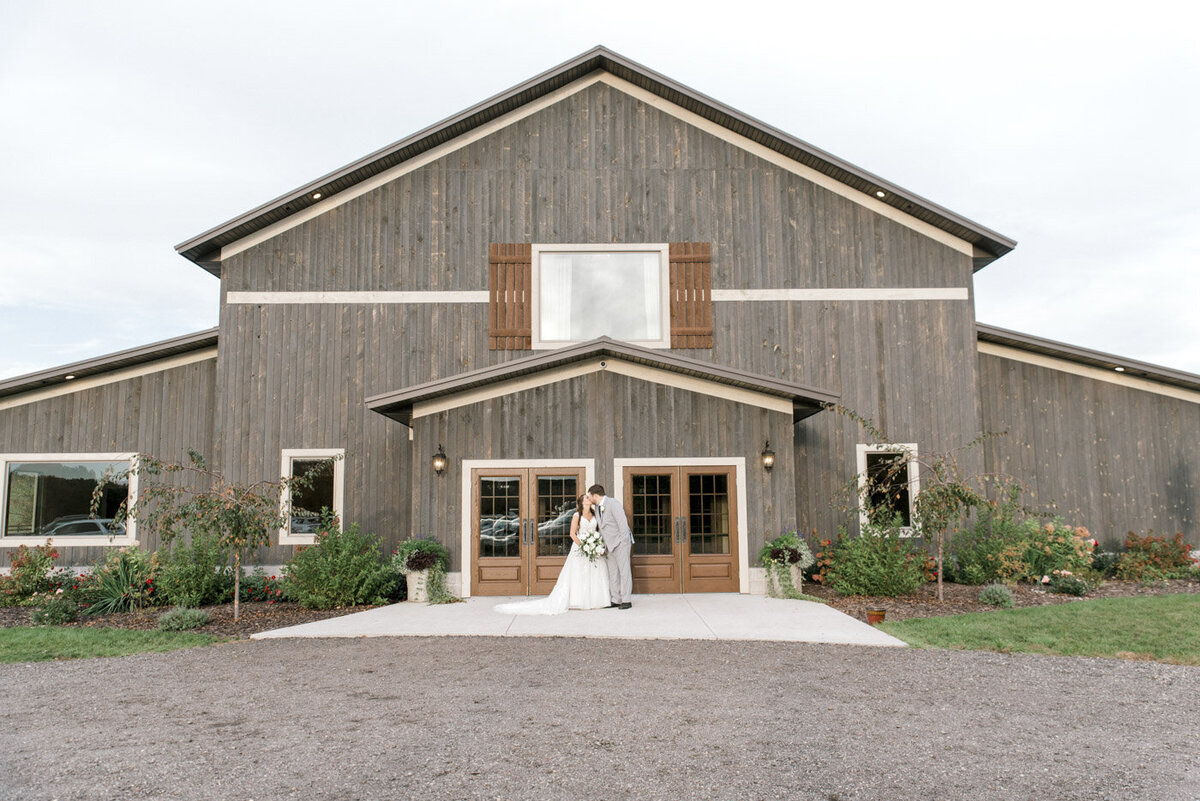 Bride and groom kiss in front of Wisconsin wedding venue
