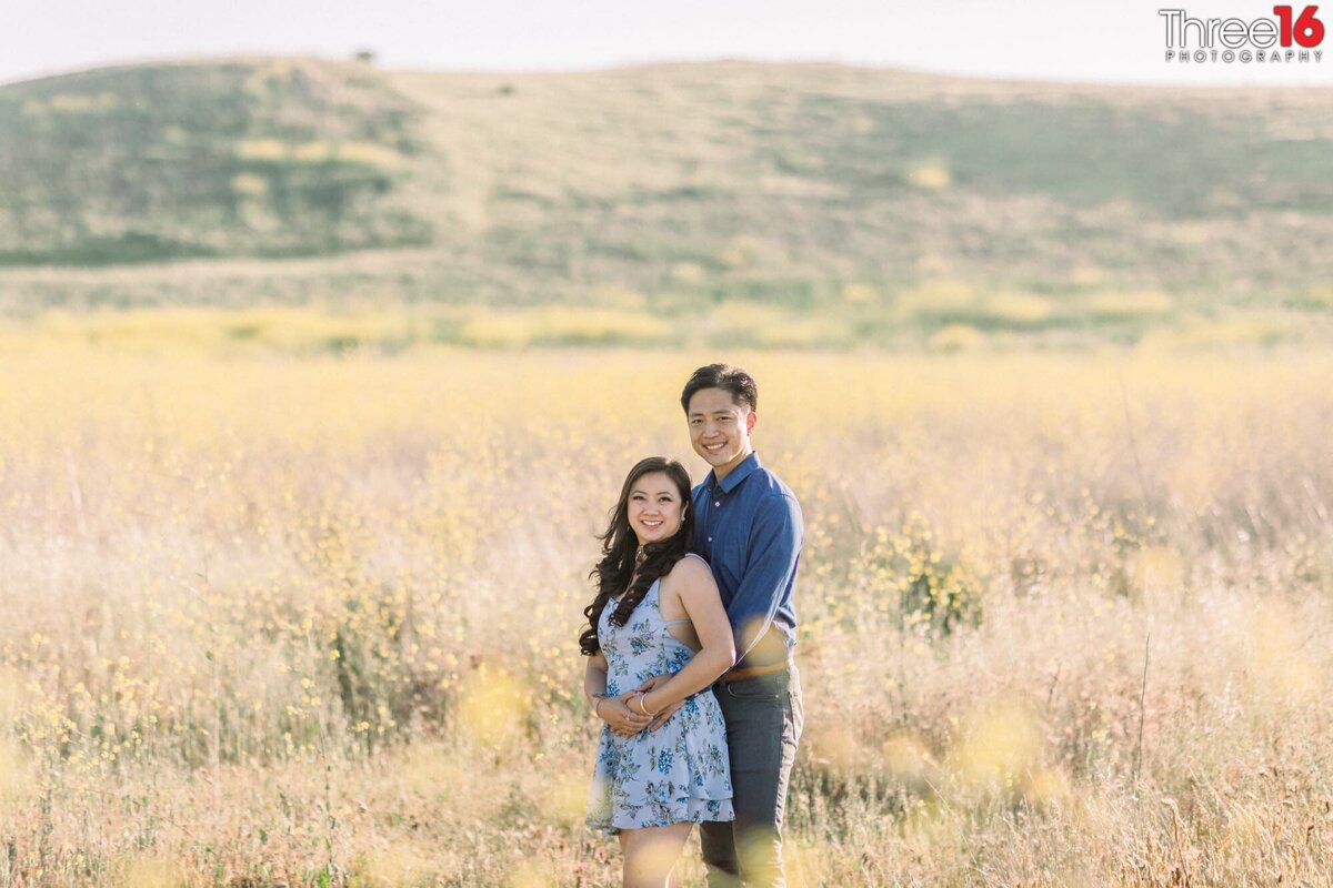 Engaged couple pose for photos in the open field of Quail Hill in Irvine