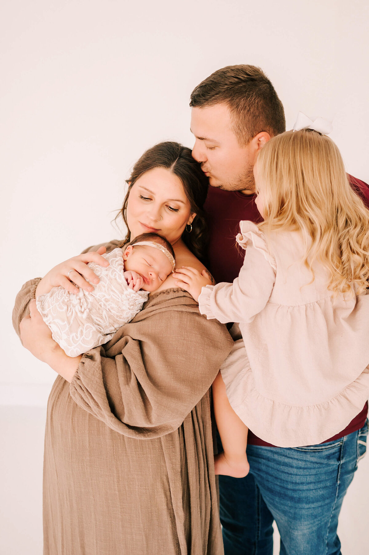 Springfield MO newborn photography of family of 4 cuddling and kissing holding newborn