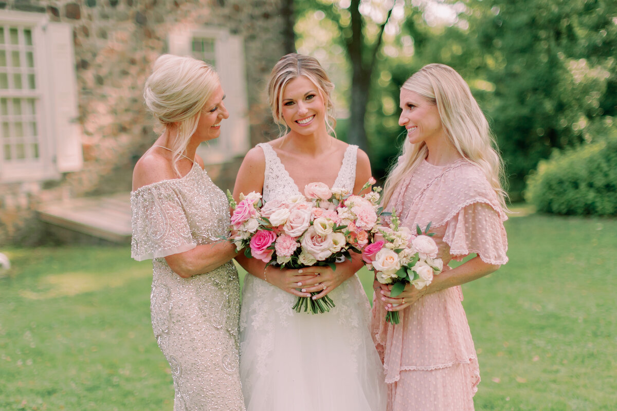 A newlywed smiling with two wedding guests on either side of them 