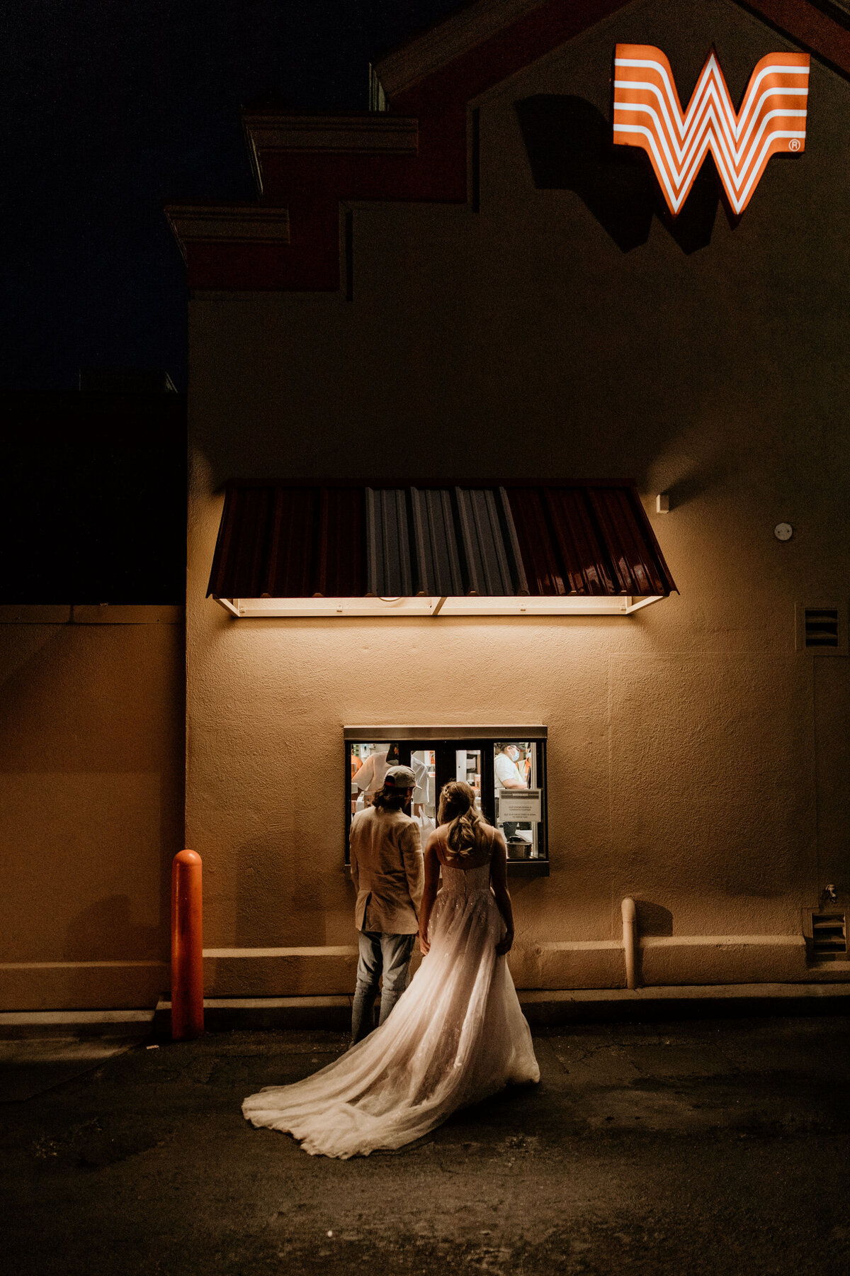 bride and groom ordering food in wedding attire at Whataburger drive thru