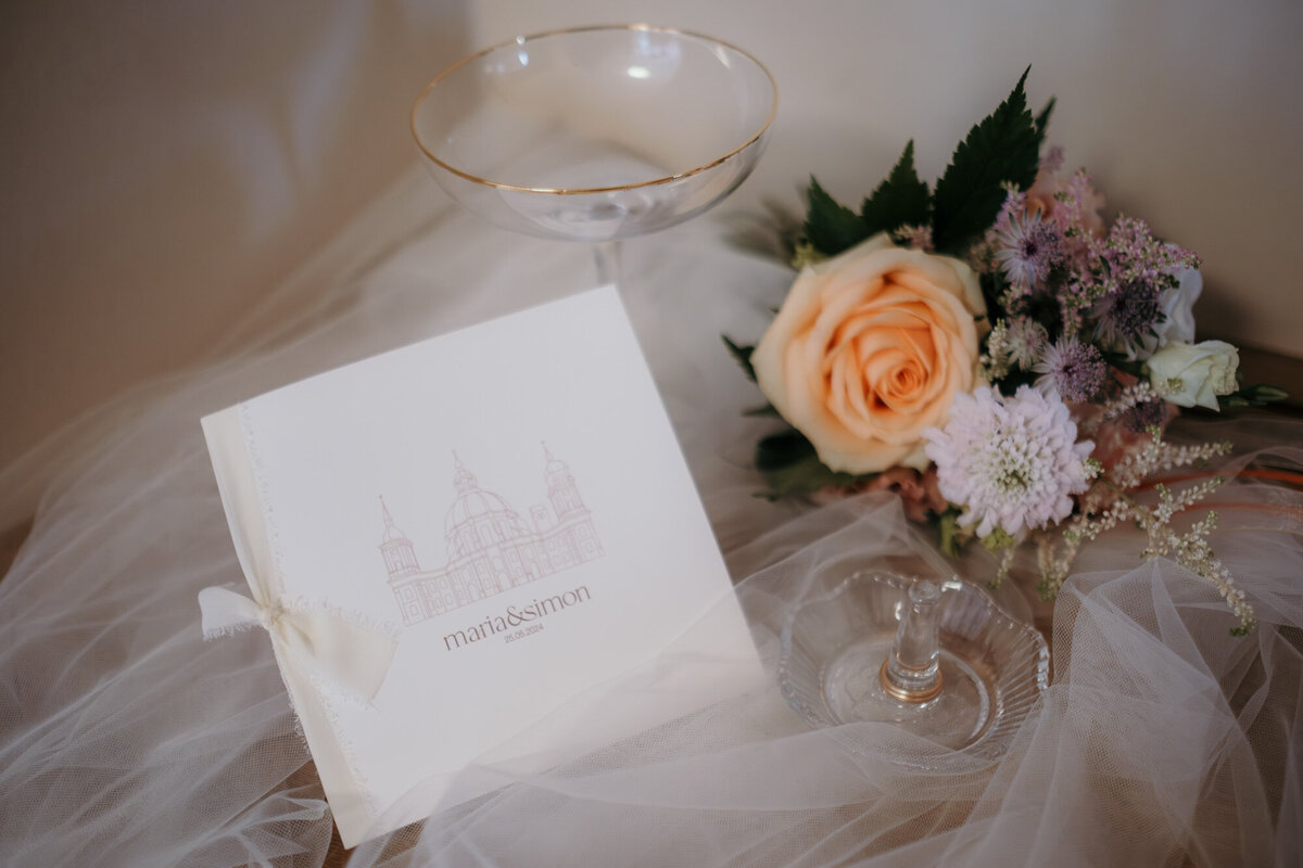 Wedding details flowers, champagne glas and stationery arranged on tull.