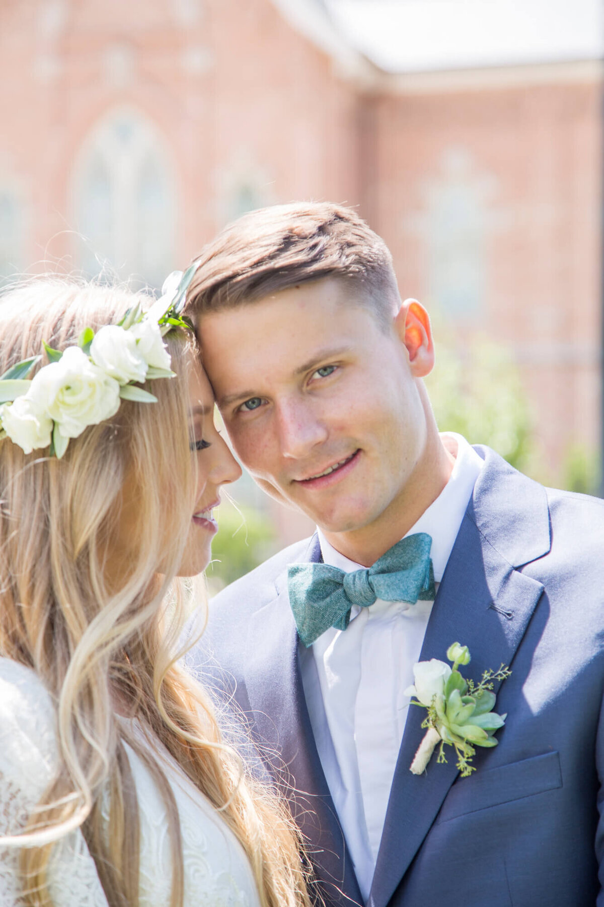 bride leaning in to a smiling groom ina blue suit