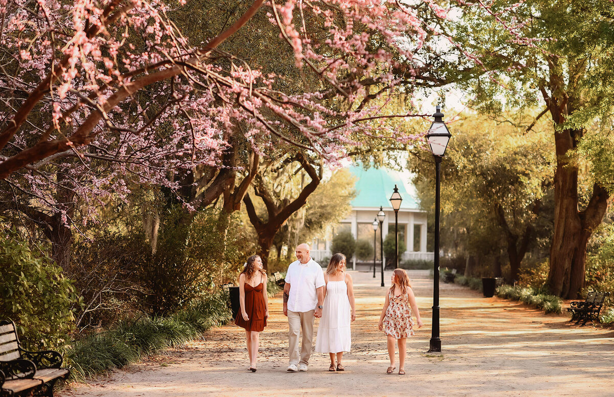 Family walks together among azalea blooms in Hampton Park during their Family Photos in Charleston, SC.