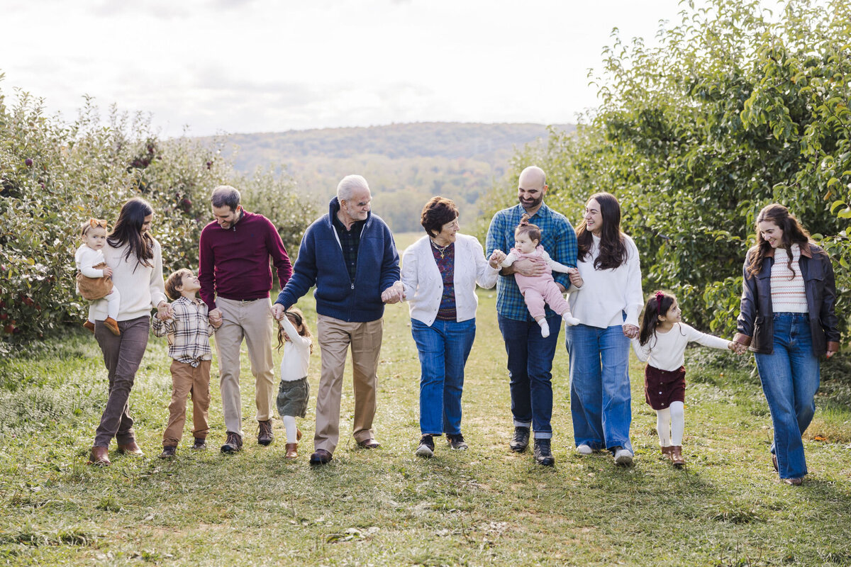 Extended family walking hand in hand through an apple orchard during a Hudson Valley family session