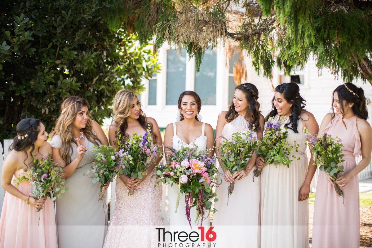 Bride smiles big as she poses with her Bridesmaids