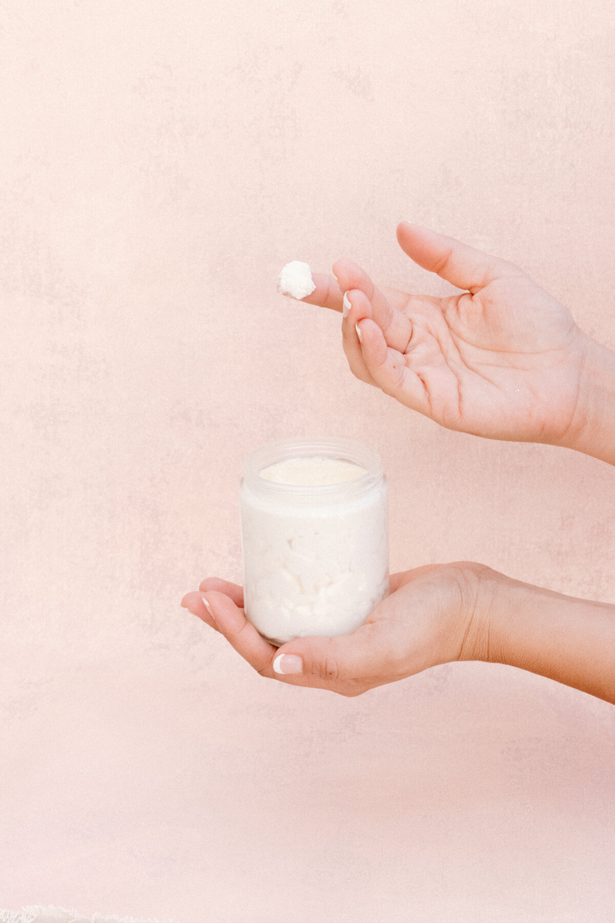 body butter jar in hands on pink background