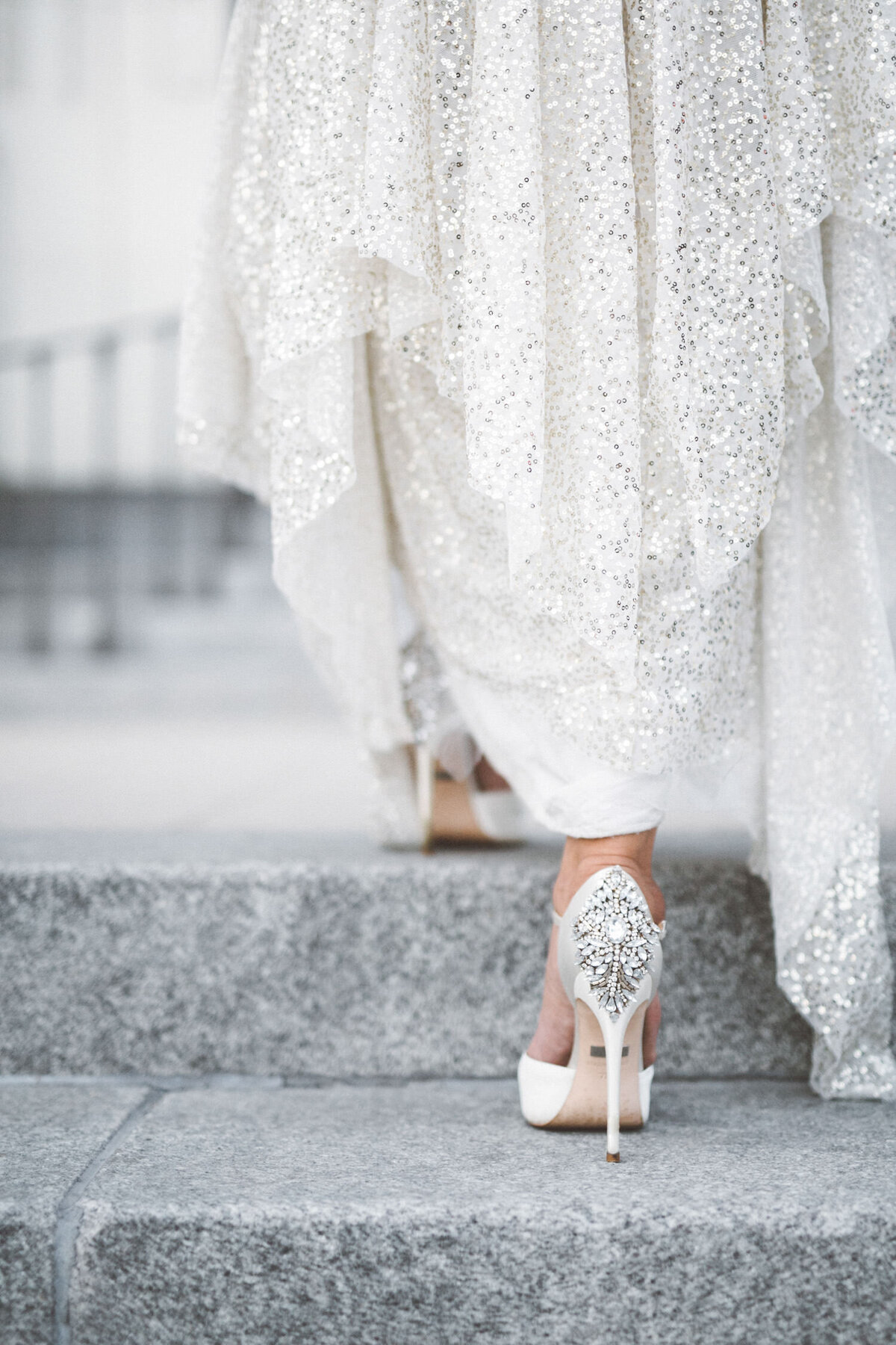 Bride walking up stairs on her wedding day in white and silver sequin wedding dress and fancy heels