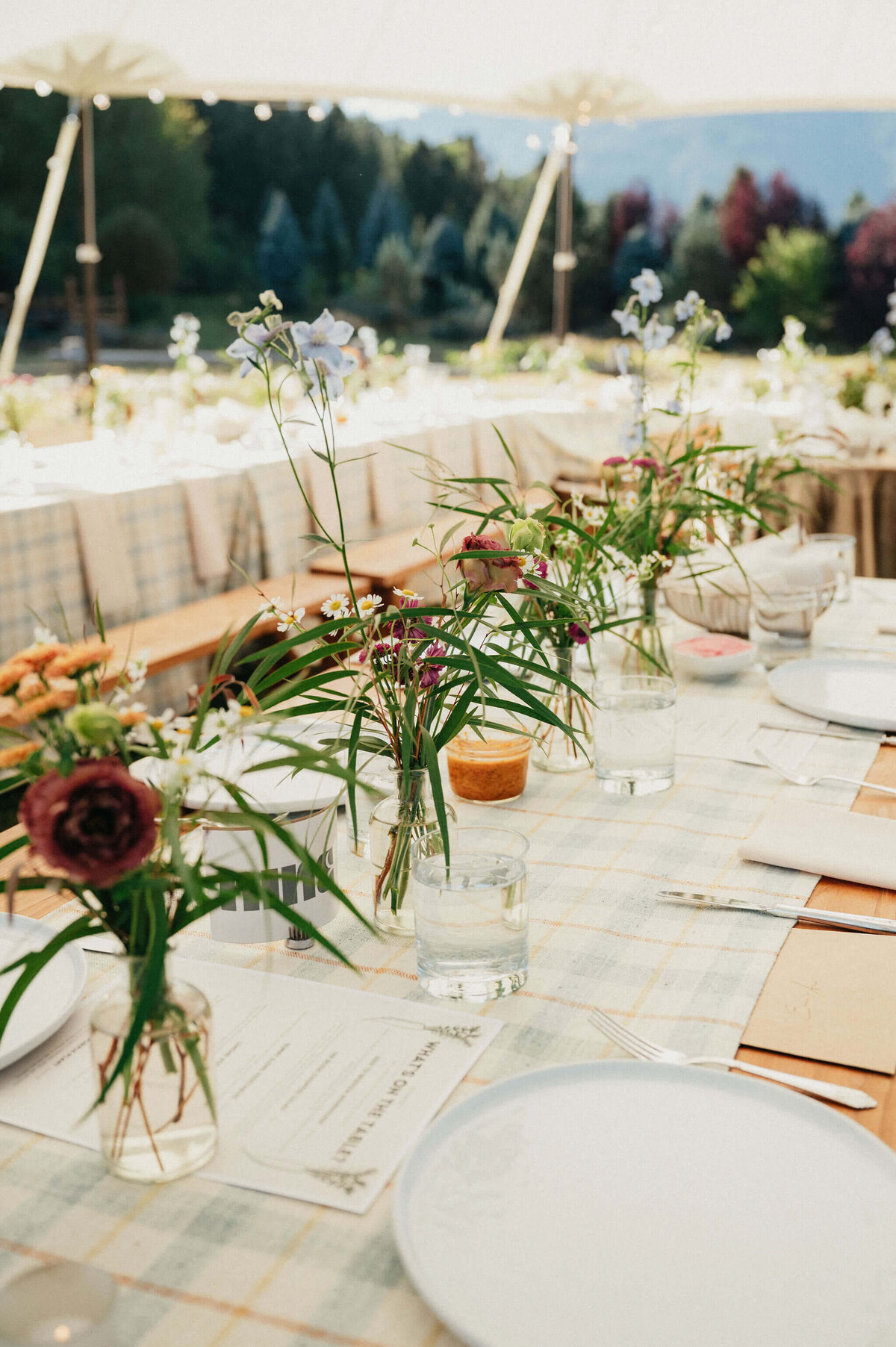 Wedding tablescape with flowers and place settings at an outdoor wedding reception. 