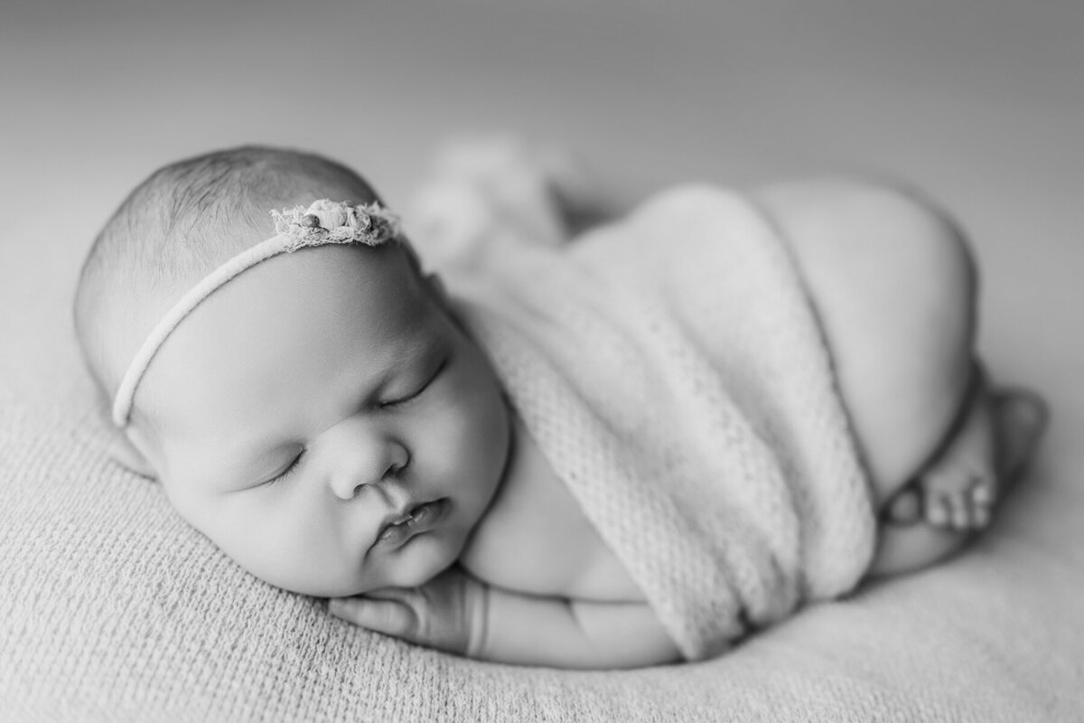 Black and white photo of newborn baby girl wrapped in a blanket