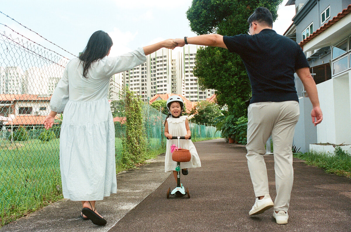 Parents playing with their daughter outdoors, creating joyful memories, a Singapore family photoshoot