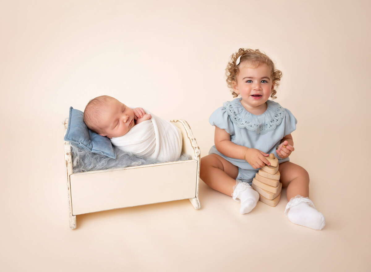 Sibling and newborn photo captured by NYC photographer in Brooklyn studio — big sister gently holding baby brother