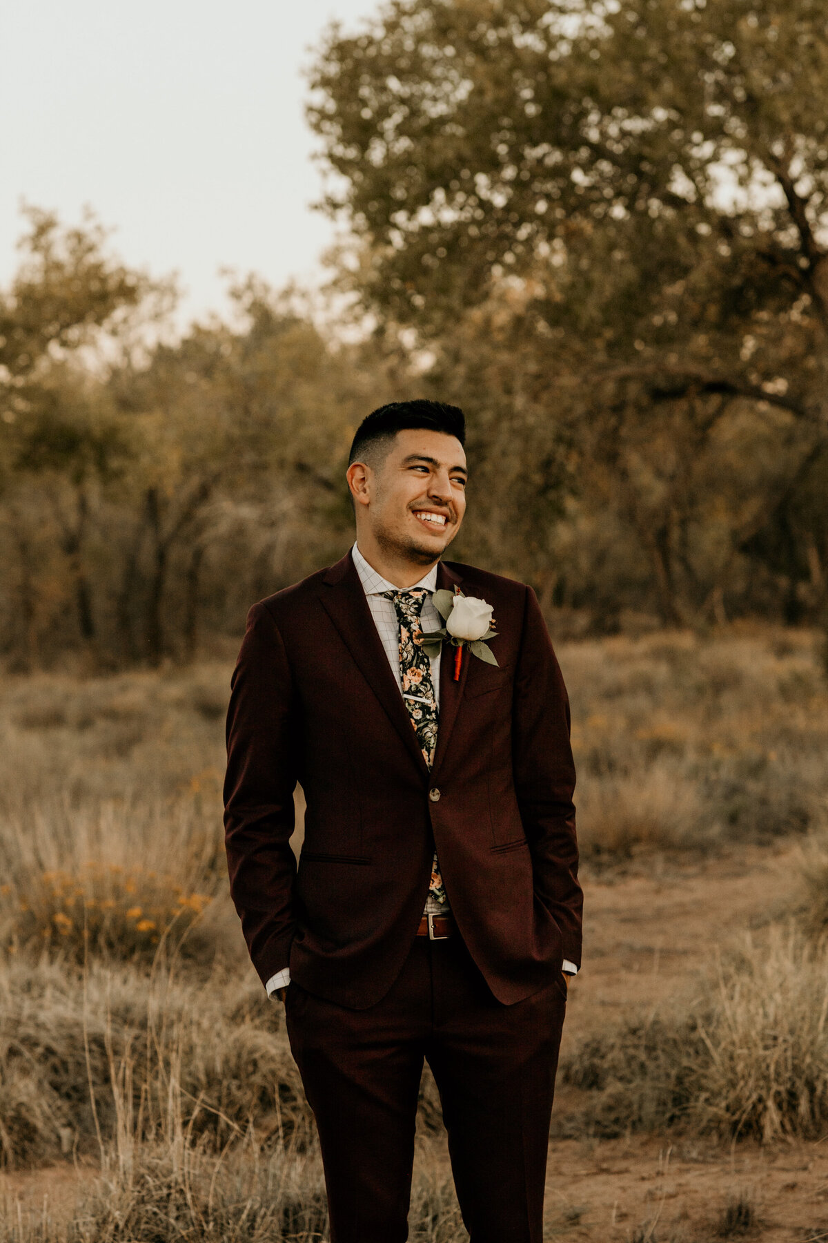 groom in a maroon suit standing in the desert