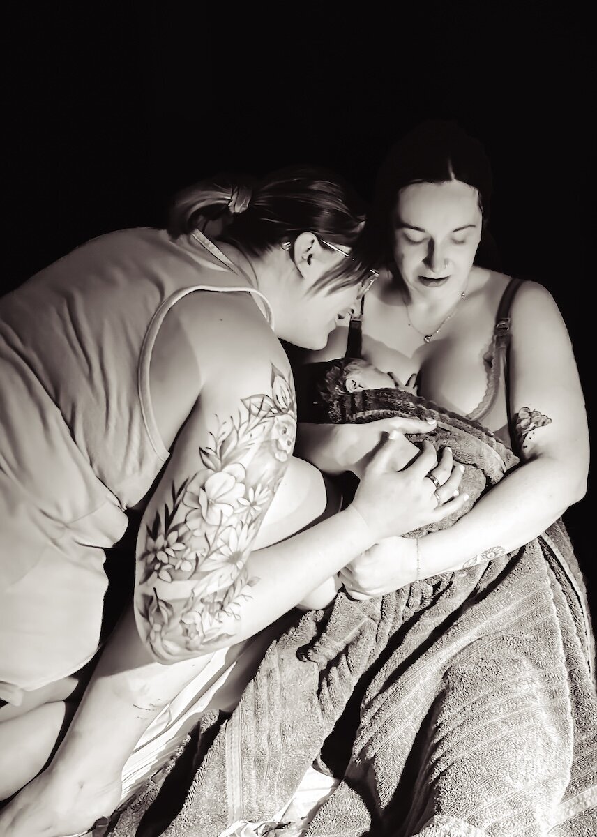 lesbian couple embrace after the birth of their child