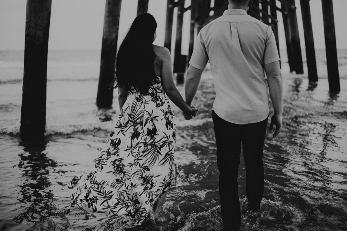 A couple holds hand under a pier