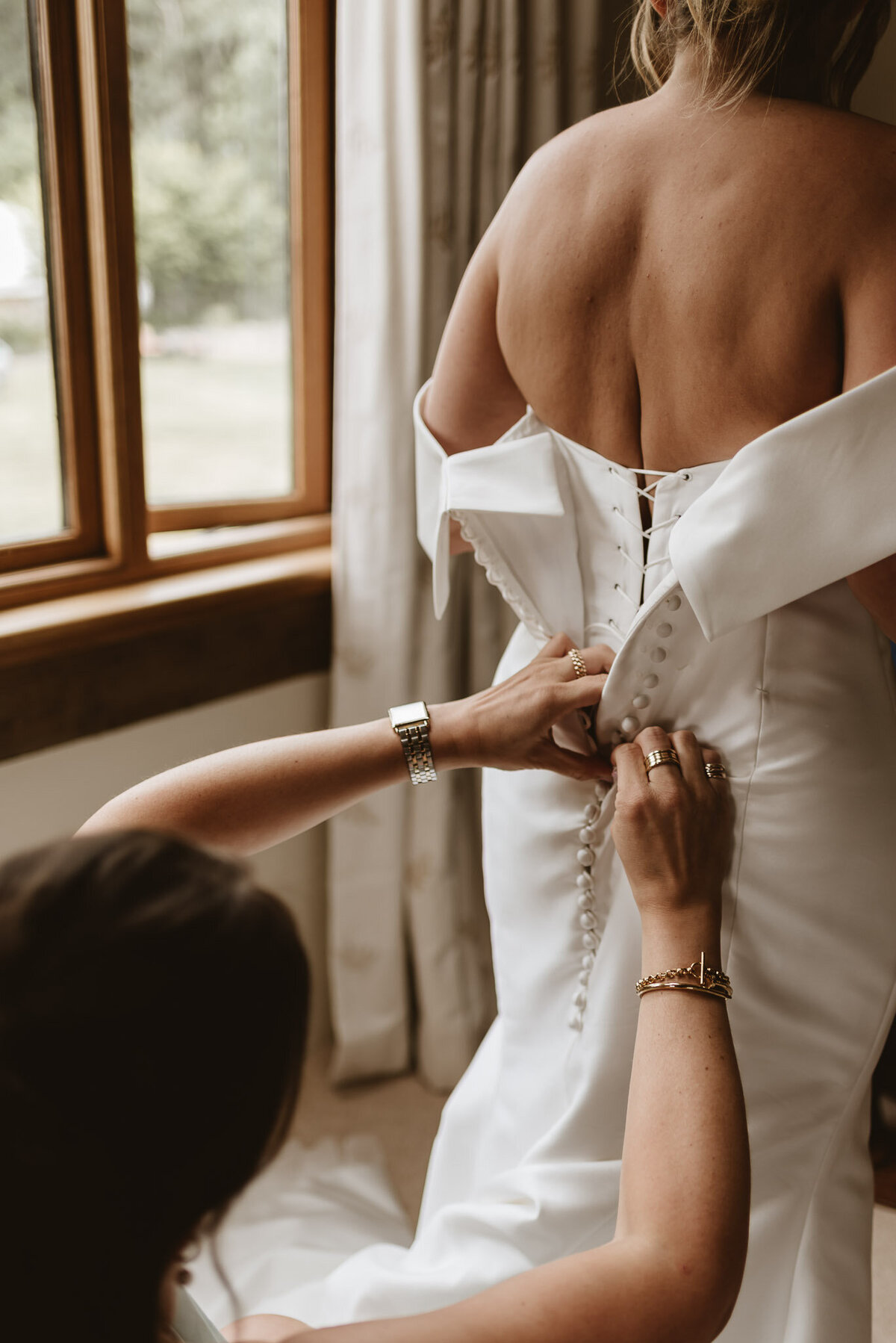 back of brides white dress being done up