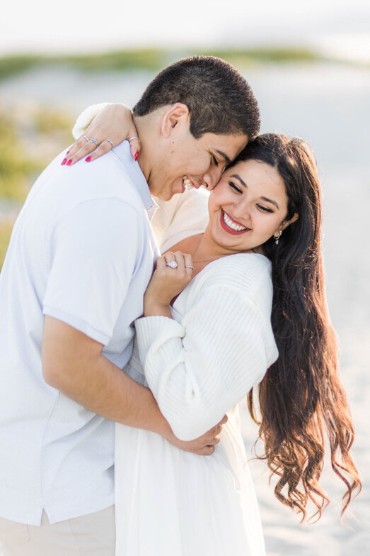 couple laughing and hugging at their engagement session at Coronado Beach in San Diego